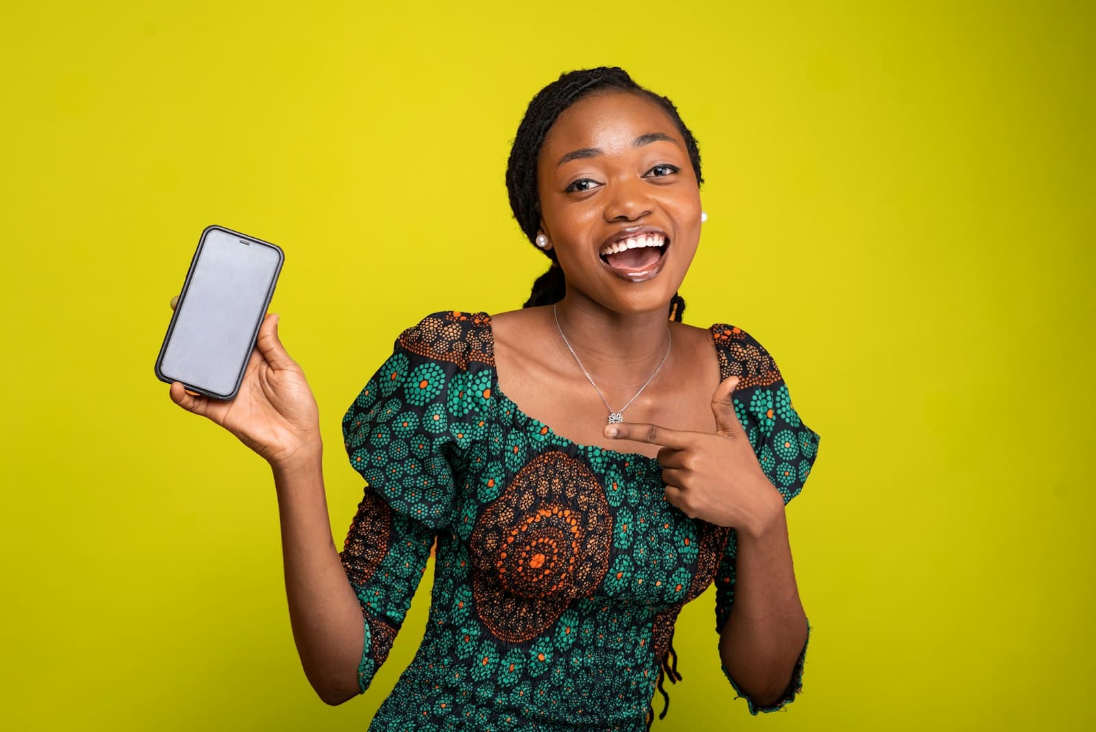 Jeune femme africaine enthousiaste montrant son téléphone